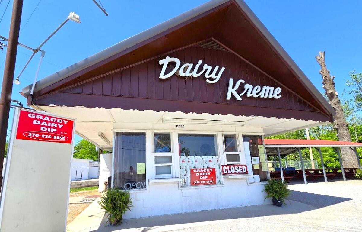 Dairy Kreme storefront with a brown gabled roof, white walls, and a 'CLOSED' sign in the window on a sunny day.