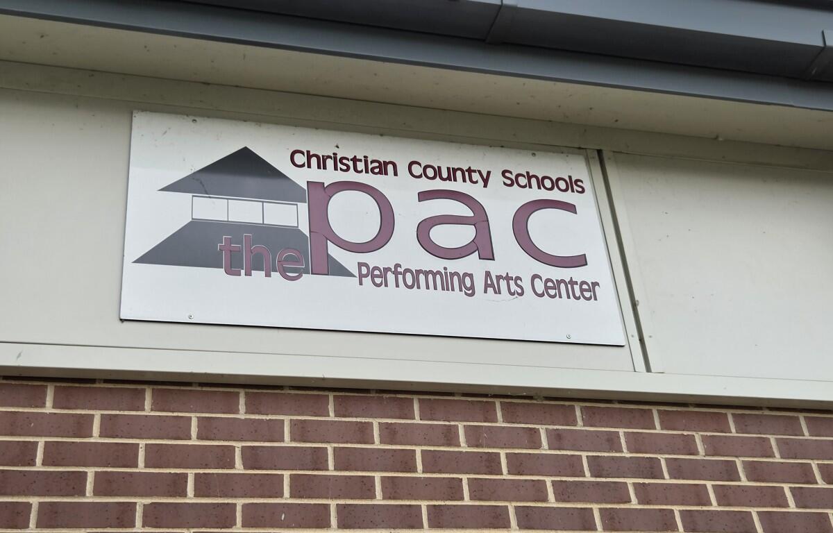 Sign reading 'Christian County Schools PAC' and 'Performing Arts Center' with a building logo on a white plaque above a brick wall