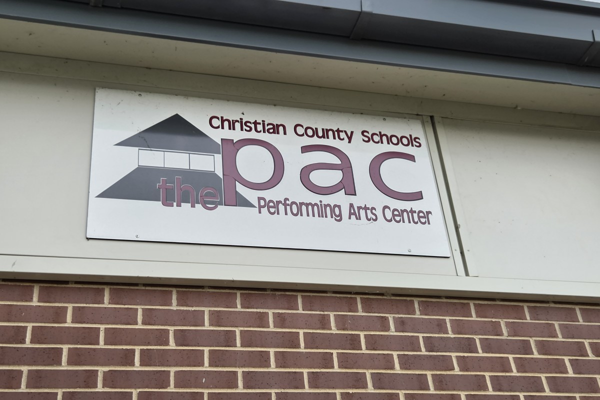 Sign reading 'Christian County Schools PAC' and 'Performing Arts Center' with a building logo on a white plaque above a brick wall