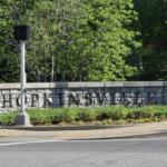 Stone wall sign reading 'Hopkinsville' with shrubs and a small traffic signal in front.