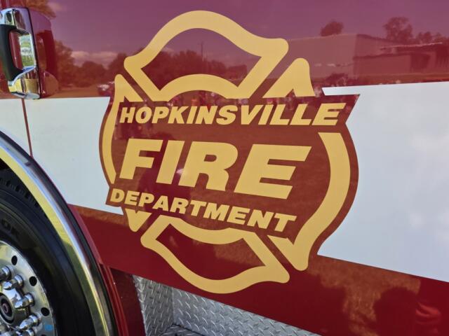Front side of a fire engine with a large Hopkinsville Fire Department emblem in gold and red, lettering visible.