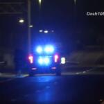 Police car at night with flashing blue emergency lights on a dim street.