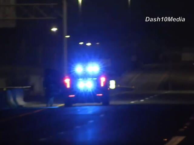 Police car at night with flashing blue emergency lights on a dim street.