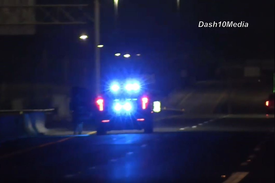 Police car at night with flashing blue emergency lights on a dim street.