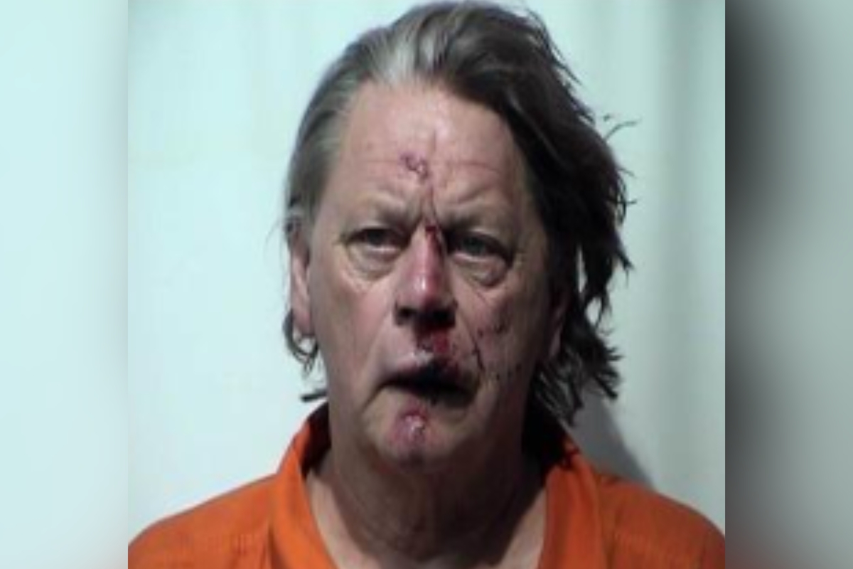 Mugshot of a middle-aged man with bruised, bloodied face wearing an orange prison jumpsuit.