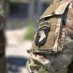 Close-up of a camouflage military uniform sleeve with an airborne unit patch featuring an eagle emblem and tan velcro area