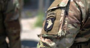 Close-up of a camouflage military uniform sleeve with an airborne unit patch featuring an eagle emblem and tan velcro area