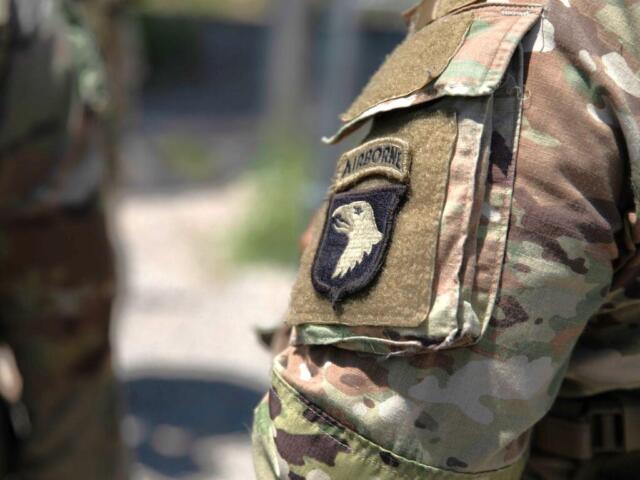 Close-up of a camouflage military uniform sleeve with an airborne unit patch featuring an eagle emblem and tan velcro area