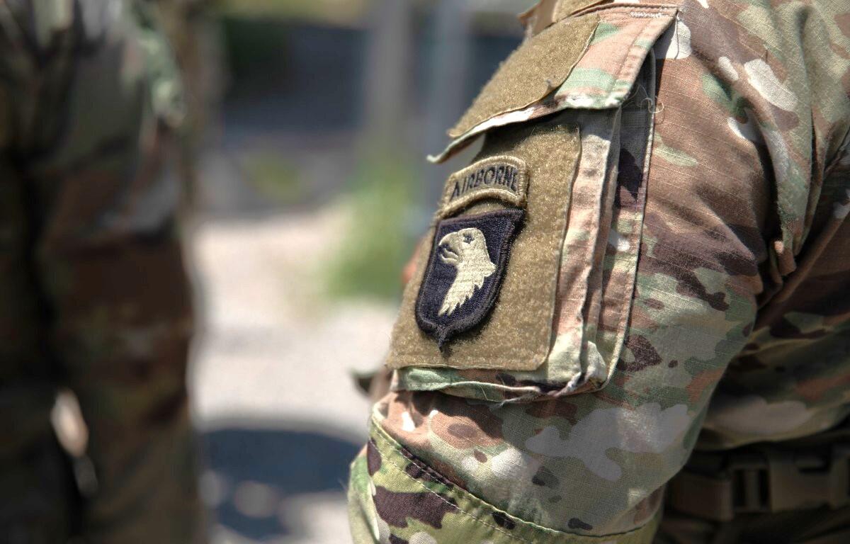 Close-up of a camouflage military uniform sleeve with an airborne unit patch featuring an eagle emblem and tan velcro area