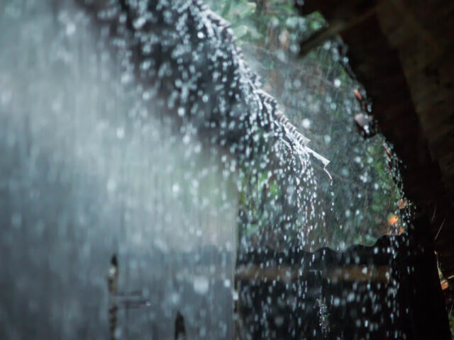 Close-up of water droplets on a glass surface with a blurred outdoor background